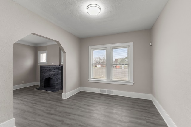 unfurnished living room featuring dark wood-type flooring, a fireplace, and a textured ceiling