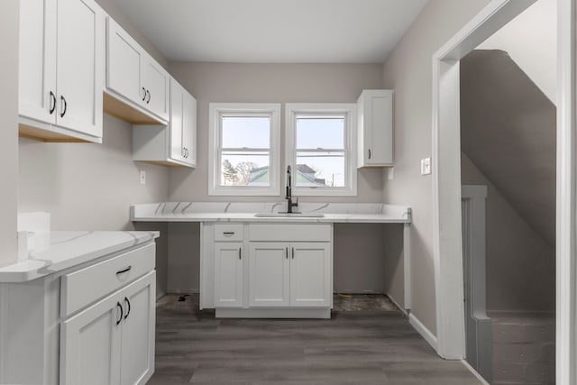 kitchen featuring white cabinetry, light stone countertops, sink, and dark wood-type flooring