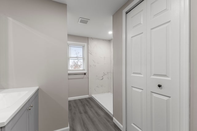 bathroom featuring hardwood / wood-style flooring, vanity, and a tile shower