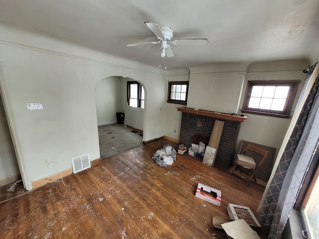 unfurnished living room featuring ceiling fan, hardwood / wood-style floors, and a brick fireplace