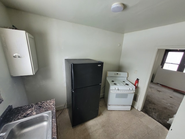 kitchen featuring white stove, sink, white cabinetry, and black fridge