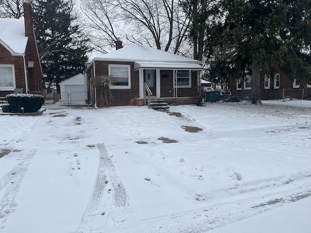 bungalow-style home with a chimney, fence, a detached garage, and brick siding