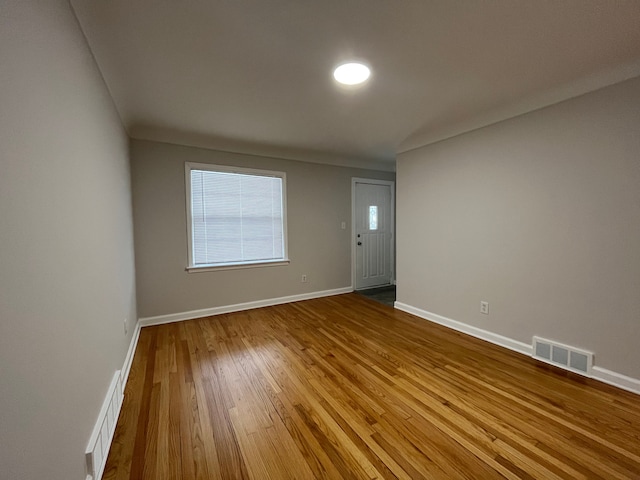 spare room featuring baseboards, visible vents, and wood finished floors