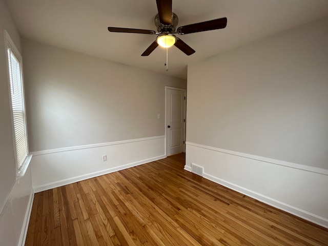 unfurnished room featuring baseboards, wood finished floors, visible vents, and a healthy amount of sunlight