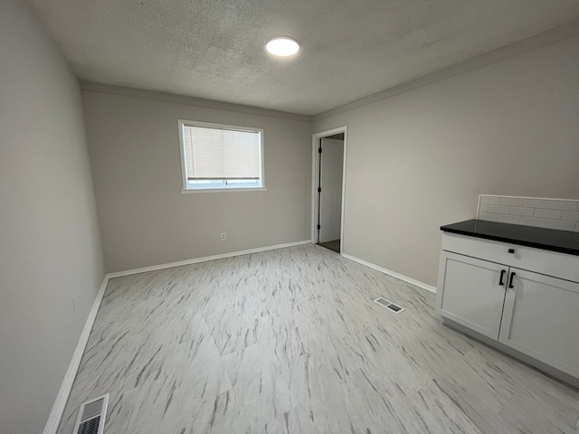 unfurnished bedroom featuring a textured ceiling, visible vents, and baseboards