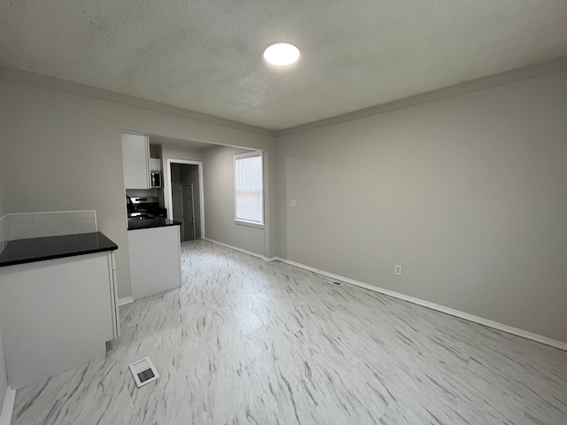 interior space featuring baseboards, visible vents, and a textured ceiling