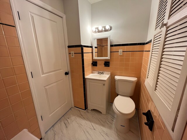 bathroom with vanity, tile walls, and toilet