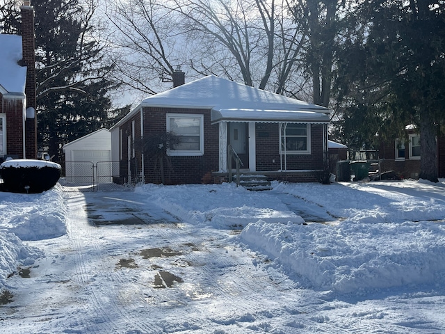 view of front of home featuring a detached garage, a chimney, an outdoor structure, and brick siding