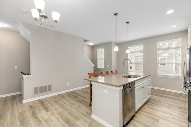 kitchen with pendant lighting, an island with sink, sink, white cabinets, and stainless steel dishwasher