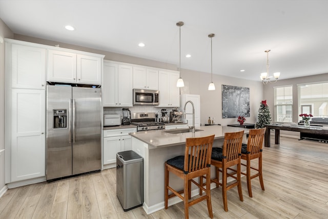 kitchen featuring sink, white cabinetry, hanging light fixtures, a center island with sink, and appliances with stainless steel finishes