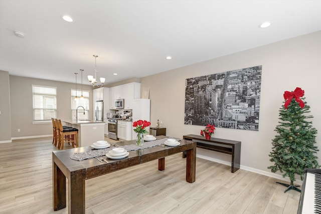 dining area featuring sink, a notable chandelier, and light hardwood / wood-style flooring