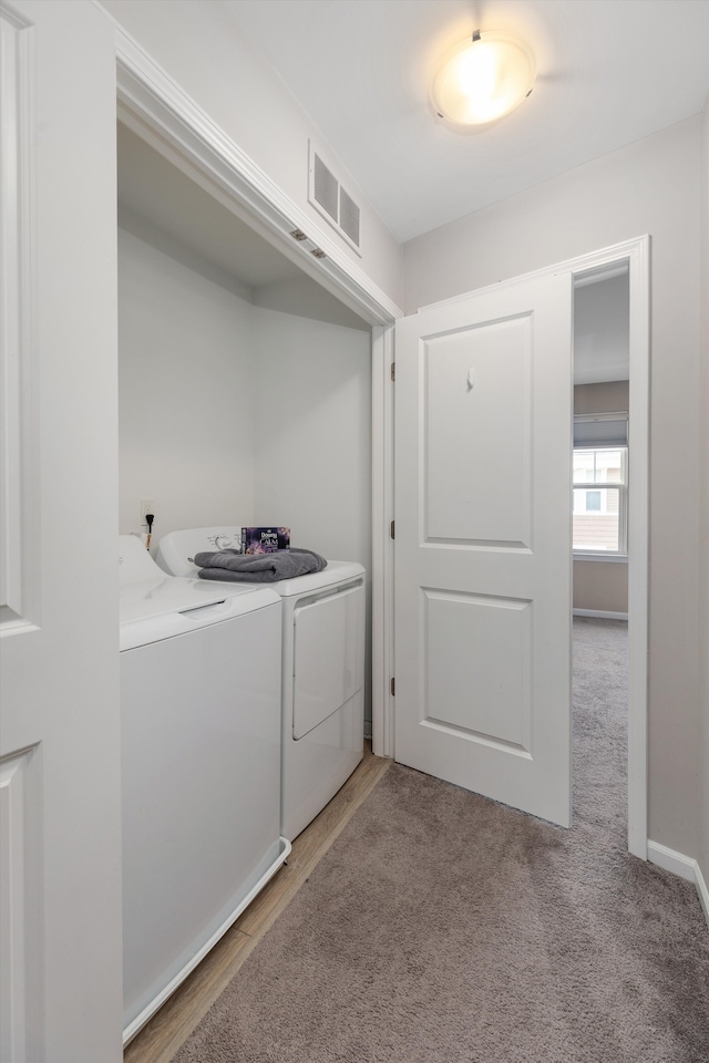 clothes washing area featuring light carpet and washer and dryer