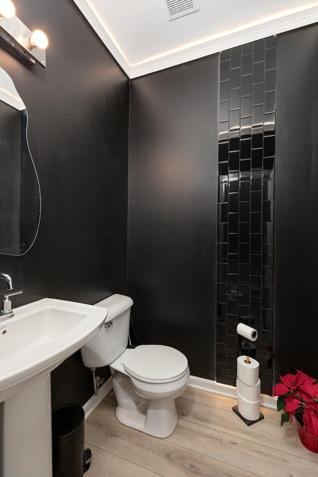 bathroom featuring crown molding, wood-type flooring, toilet, and sink