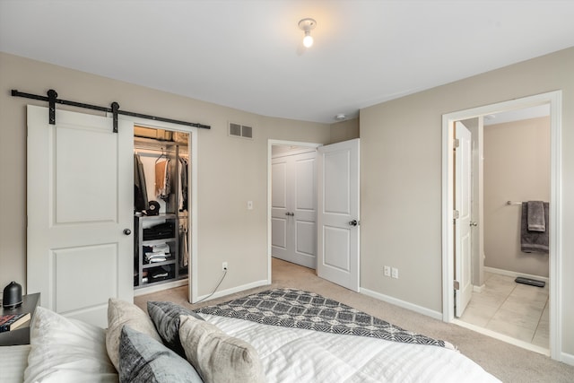 carpeted bedroom featuring ensuite bathroom, a barn door, a spacious closet, and a closet