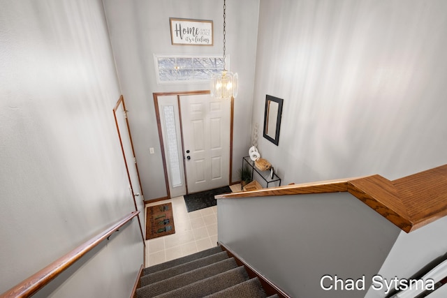 staircase with an inviting chandelier, tile patterned floors, and a high ceiling