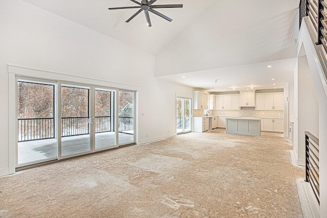 unfurnished living room featuring ceiling fan, sink, and high vaulted ceiling