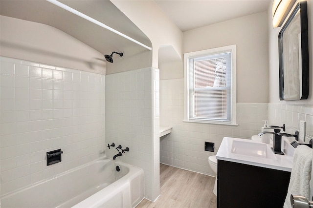 full bathroom featuring bathtub / shower combination, tile walls, hardwood / wood-style flooring, vanity, and toilet