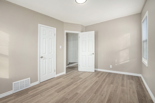 unfurnished bedroom with crown molding and light hardwood / wood-style floors