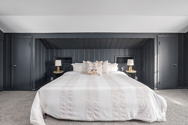 carpeted bedroom with vaulted ceiling and wood walls