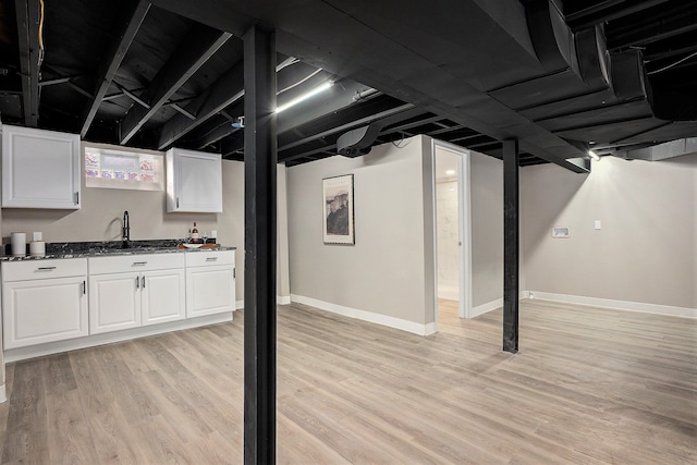 basement with light hardwood / wood-style floors and sink