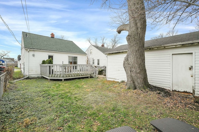 rear view of house featuring a lawn and a deck