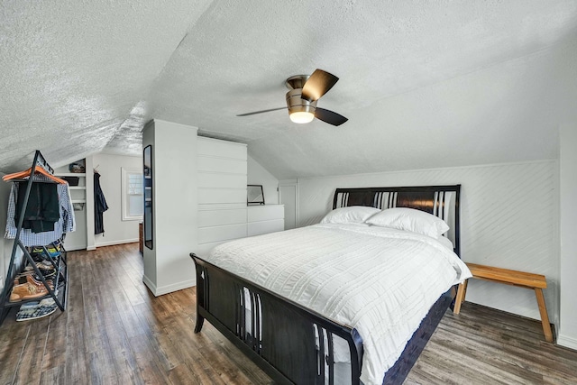 bedroom featuring vaulted ceiling, dark hardwood / wood-style flooring, a textured ceiling, and ceiling fan