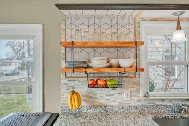 details featuring hanging light fixtures, light stone countertops, and sink