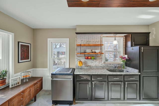 kitchen featuring sink, backsplash, light stone countertops, and hanging light fixtures