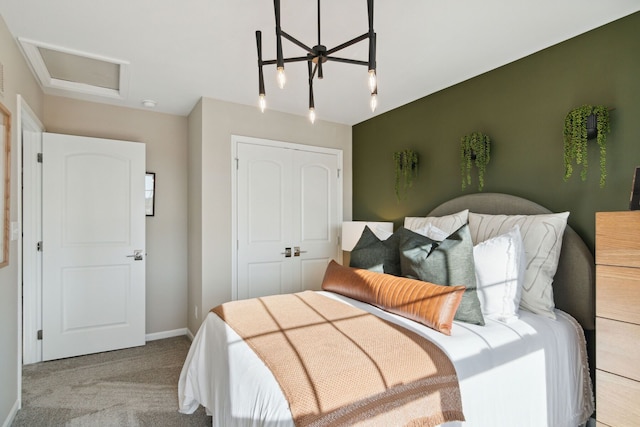 carpeted bedroom with a closet, baseboards, and attic access