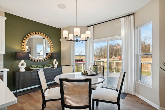 dining area with a notable chandelier, baseboards, and wood finished floors