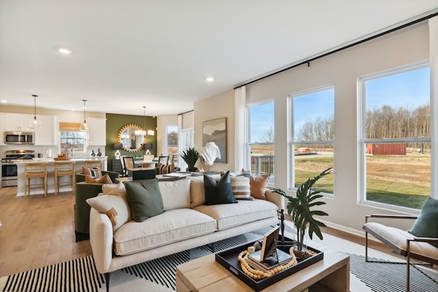 living area featuring recessed lighting, baseboards, light wood-type flooring, and an inviting chandelier