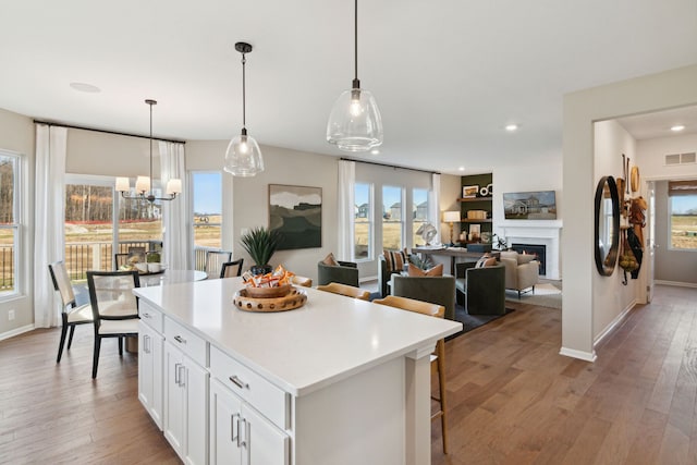 kitchen featuring visible vents, white cabinetry, a kitchen island, and light wood finished floors