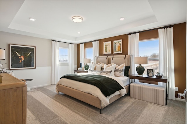 carpeted bedroom with multiple windows, a raised ceiling, and radiator heating unit