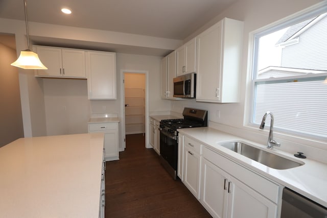 kitchen featuring a sink, appliances with stainless steel finishes, a wealth of natural light, and white cabinetry