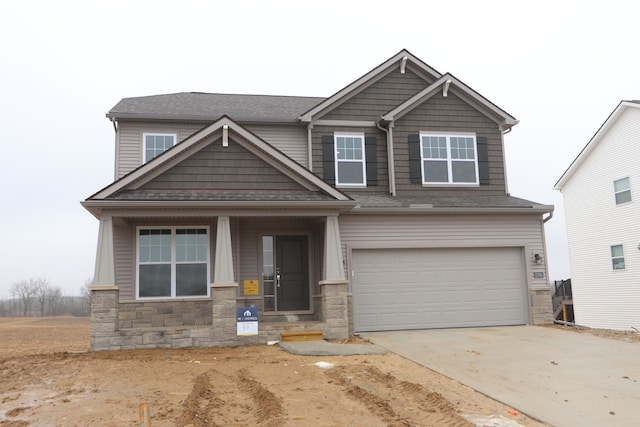 craftsman-style home featuring concrete driveway, a garage, and stone siding