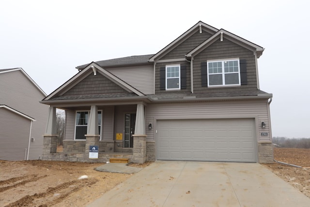 craftsman-style home with a porch, stone siding, driveway, and an attached garage