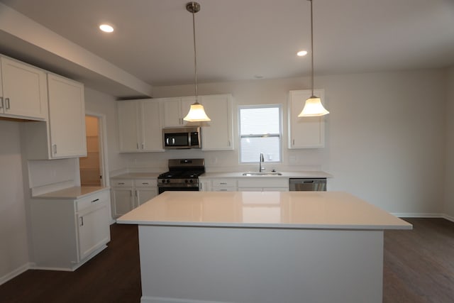 kitchen featuring a kitchen island, dark wood-style flooring, stainless steel appliances, and a sink