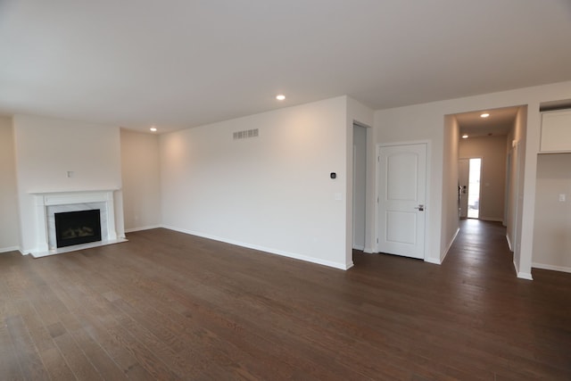 unfurnished living room featuring baseboards, visible vents, a premium fireplace, dark wood finished floors, and recessed lighting