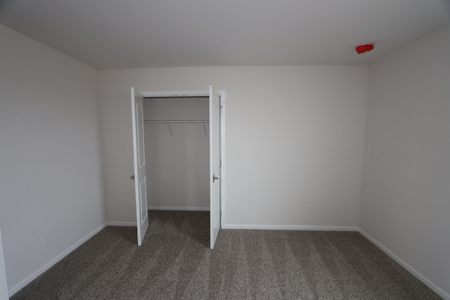 unfurnished bedroom with a closet, baseboards, and carpet floors