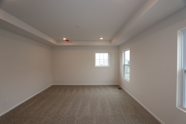 carpeted empty room with recessed lighting, baseboards, and a raised ceiling