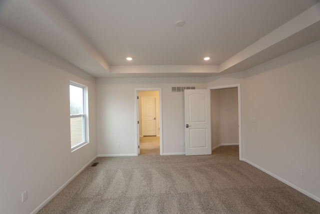 interior space featuring a tray ceiling, visible vents, baseboards, and recessed lighting