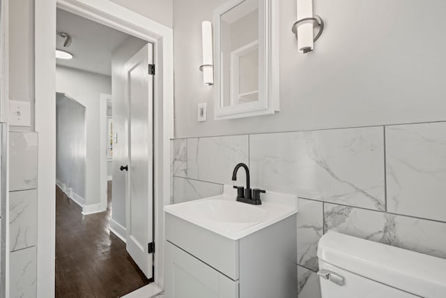 bathroom featuring hardwood / wood-style floors, vanity, tile walls, and toilet