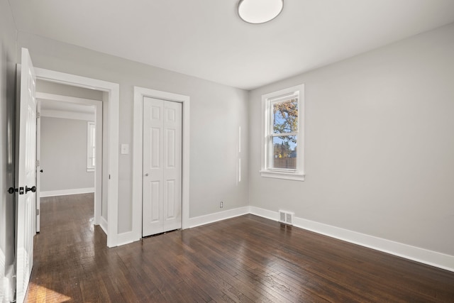 unfurnished bedroom with dark hardwood / wood-style floors and a closet