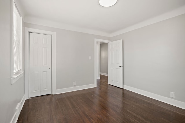 unfurnished bedroom with dark wood-type flooring and a closet