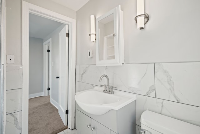 bathroom featuring vanity, toilet, and tile walls