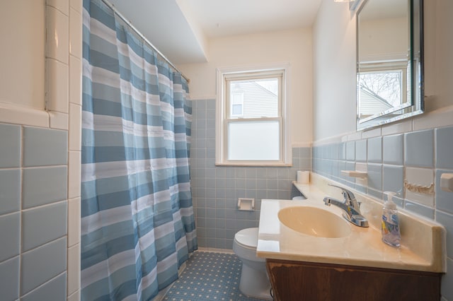 bathroom with tile walls, vanity, plenty of natural light, and toilet