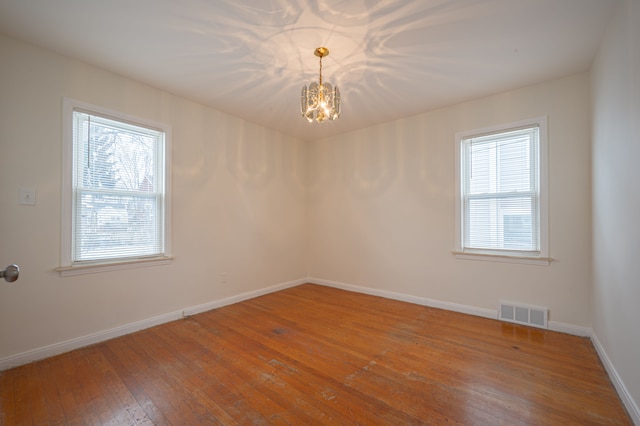 unfurnished room with hardwood / wood-style floors and a notable chandelier