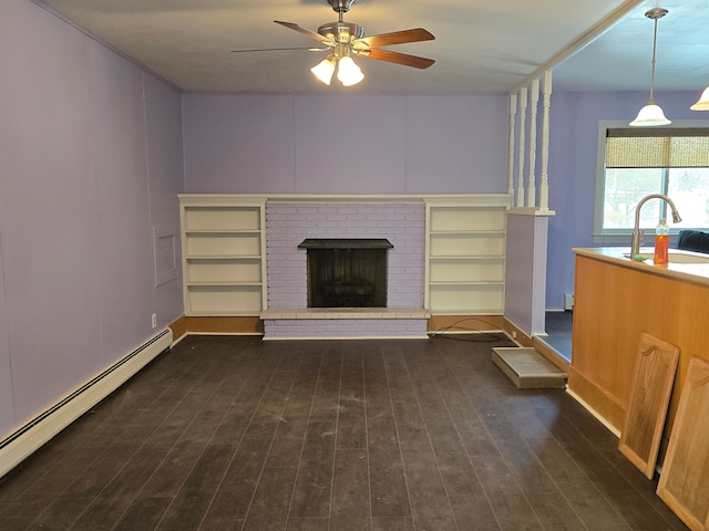 unfurnished living room featuring sink, ceiling fan, dark hardwood / wood-style floors, a fireplace, and a baseboard radiator