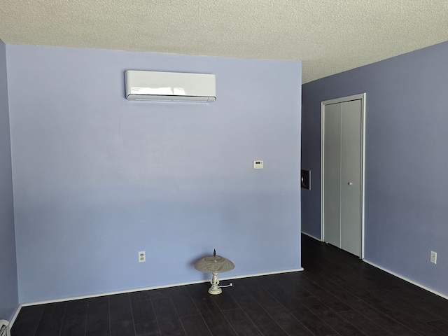 unfurnished room featuring dark hardwood / wood-style floors, a textured ceiling, and a wall unit AC