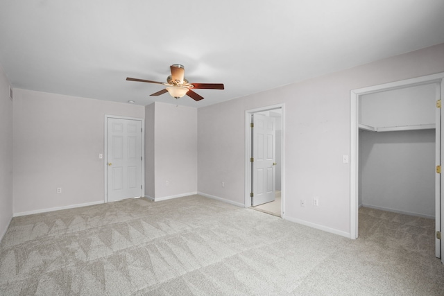 unfurnished bedroom with a spacious closet, light carpet, and ceiling fan